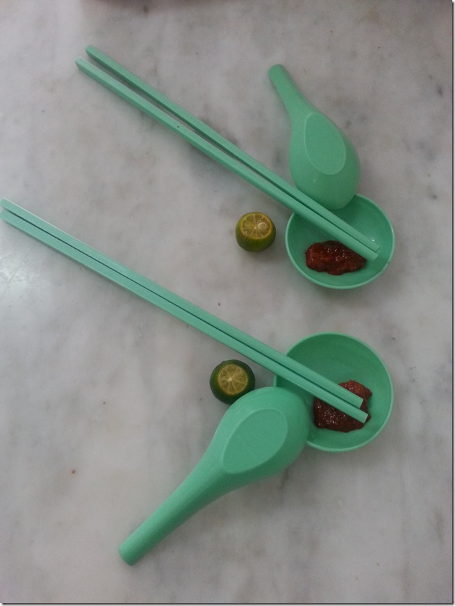 Preparation for Laksa Sarawak - chopsticks, soup spoon, lime, and hot sauce.