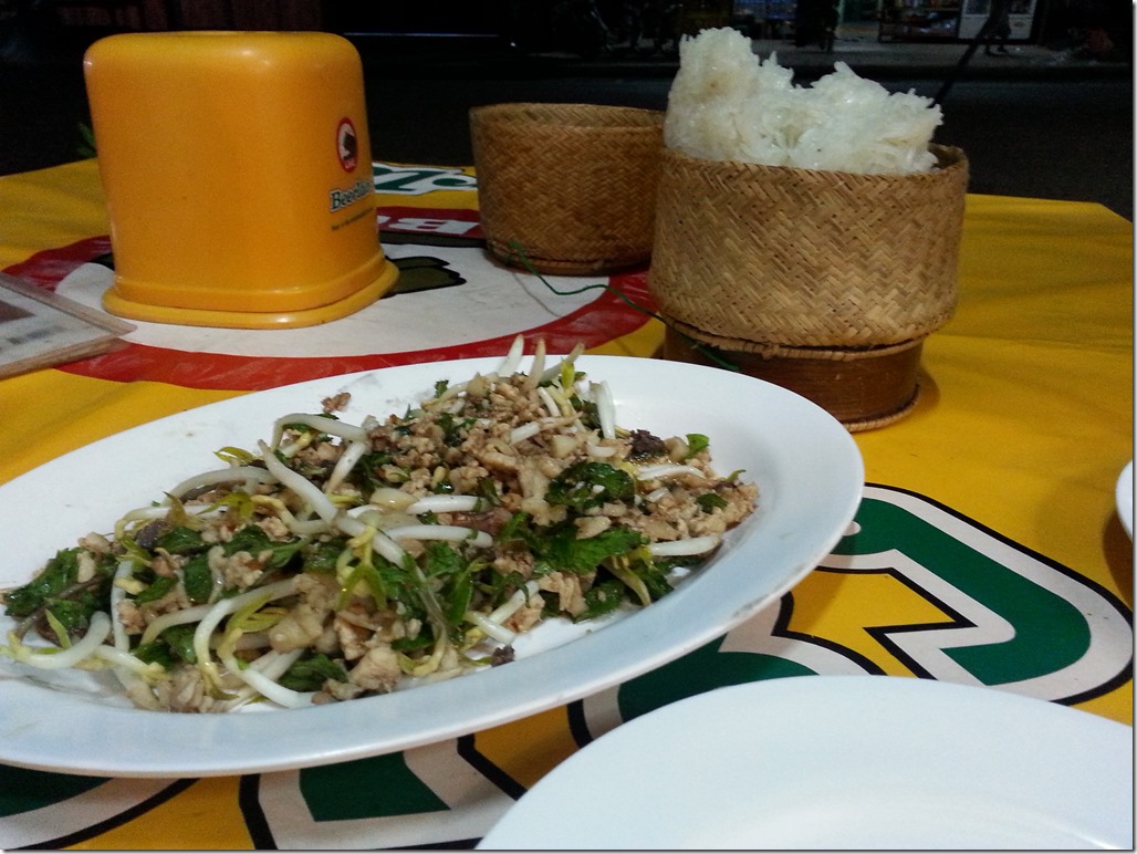 Laap with sticky rice in the background (in the small whicker bowl).
